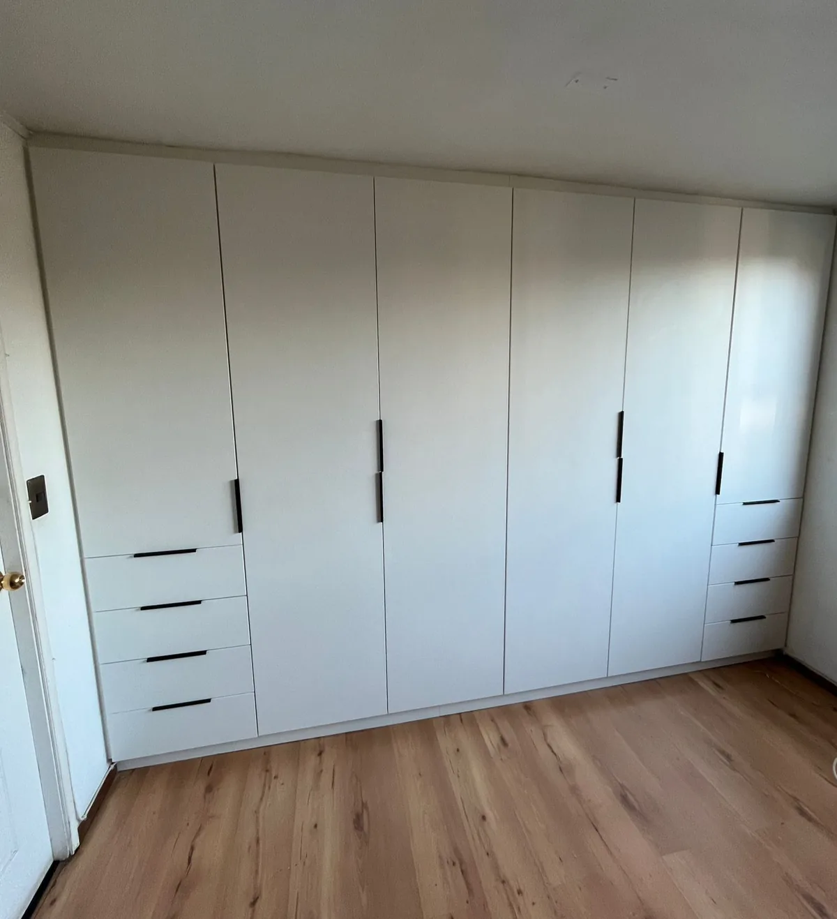 Closet blanco a medida con cajoneras laterales y tiradores negros