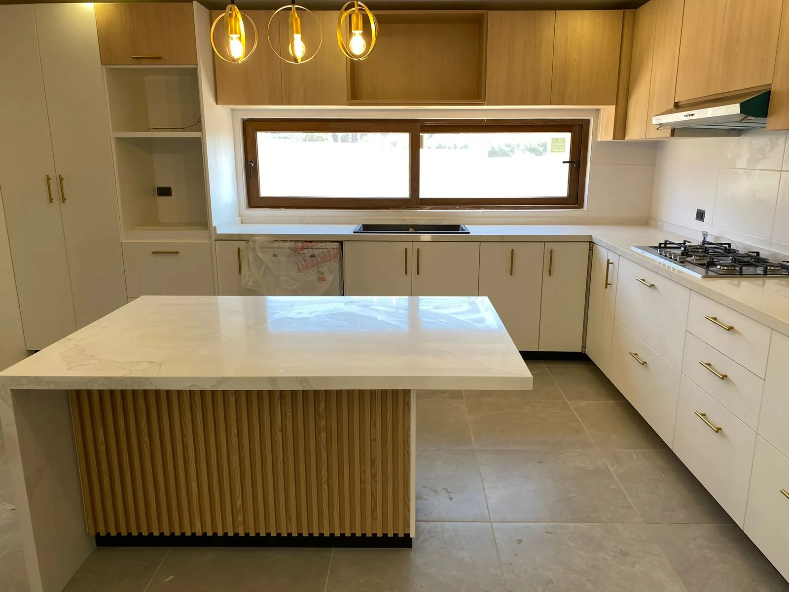 Cocina a medida con isla central, muebles de madera y cubierta blanca