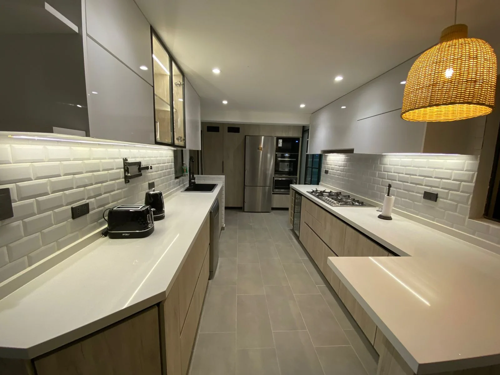 Cocina terminada con muebles bajos, cubierta blanca, backsplash tipo ladrillo y luz LED